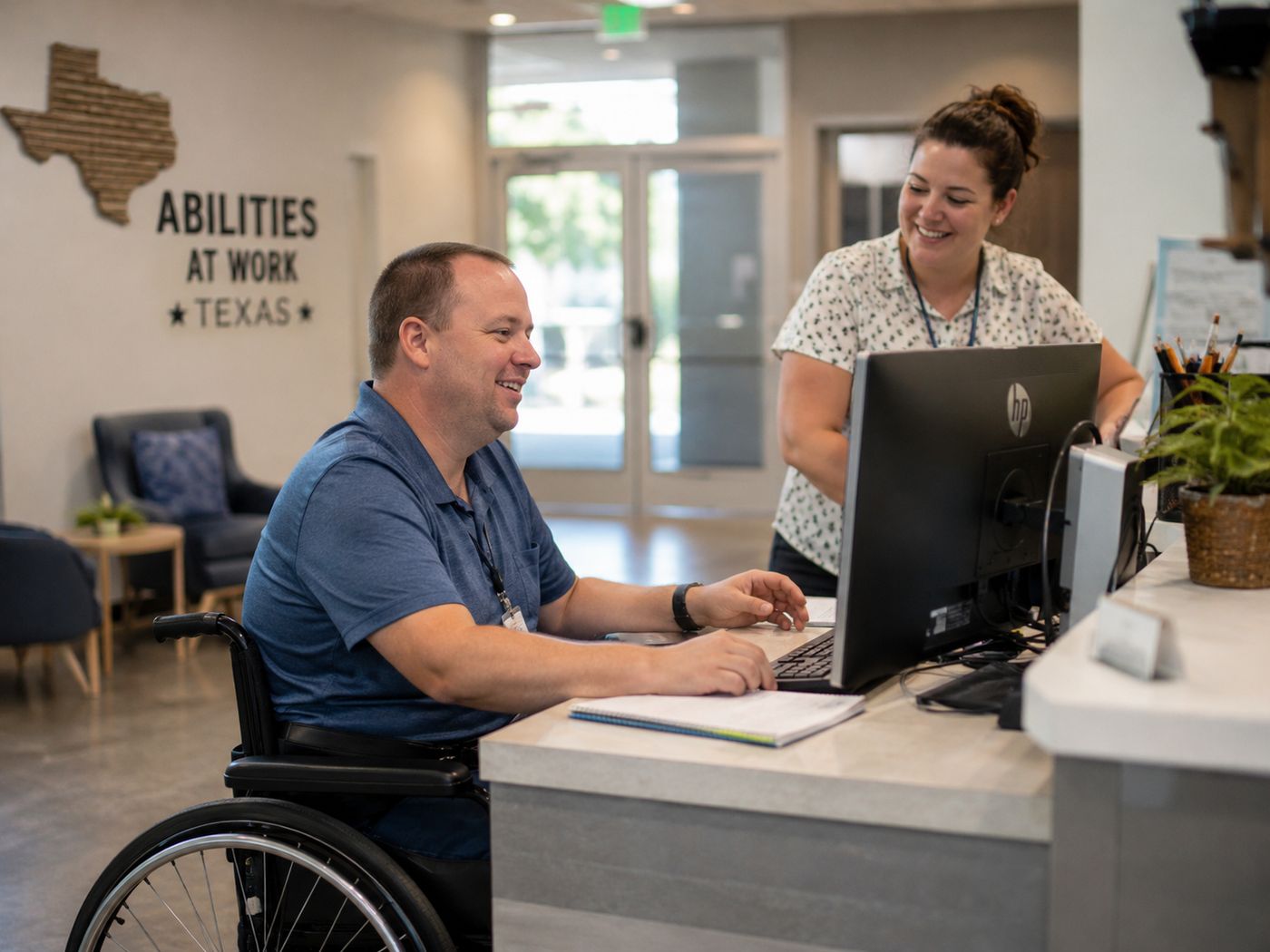 A man using a wheelchair working at a reception desk with a colleague beside him.